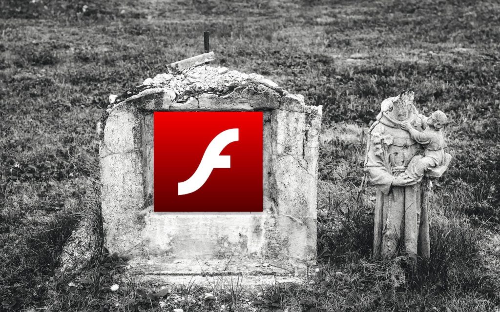 A weathered, old gravestone displays the Adobe Flash Player logo. Beside it stands a worn statue of a headless figure holding a child. The scene suggests a symbolic death of Flash Player.
