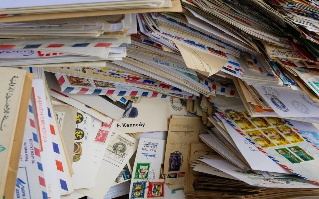 A large pile of assorted letters and envelopes, many with colorful stamps, air mail markings, and handwritten addresses, stacked closely together in a chaotic arrangement.