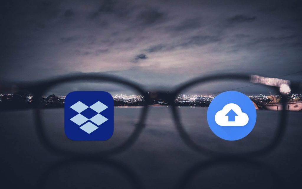 A blurred cityscape at night is seen through eyeglasses, with the Dropbox logo on the left lens and a cloud upload icon on the right lens, both in sharp focus.