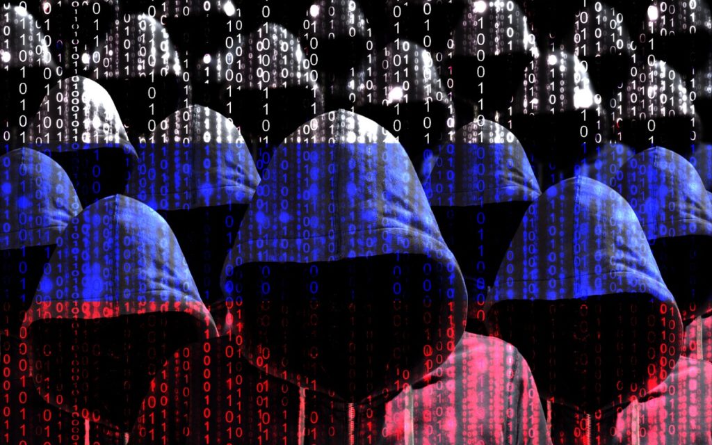 Several hooded figures with obscured faces stand together, overlaid with binary code. The figures are tinted in blue, white, and red, resembling the Russian flag. The image conveys a theme of cybercrime or hacking.