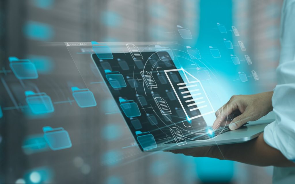A person using a laptop with digital file and folder icons hovering above the screen, representing data management or digital file storage in a modern technology environment.
