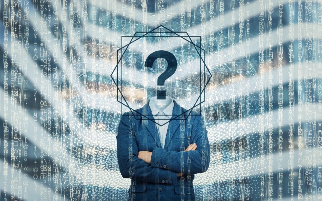 A person in a suit with arms crossed stands in front of a digital background. Their face is obscured by a large question mark inside a geometric frame, suggesting mystery or anonymity. Binary code overlays the image.