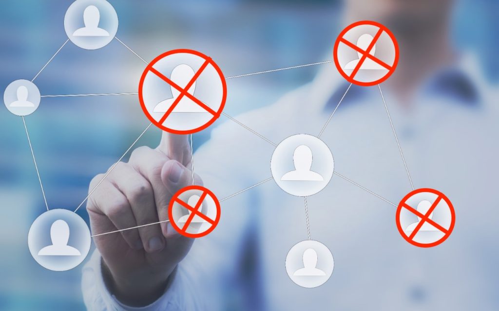 A person touches a screen displaying a network of user icons, with several icons crossed out in red, symbolizing removal or disconnection from the network. The background is blurred.