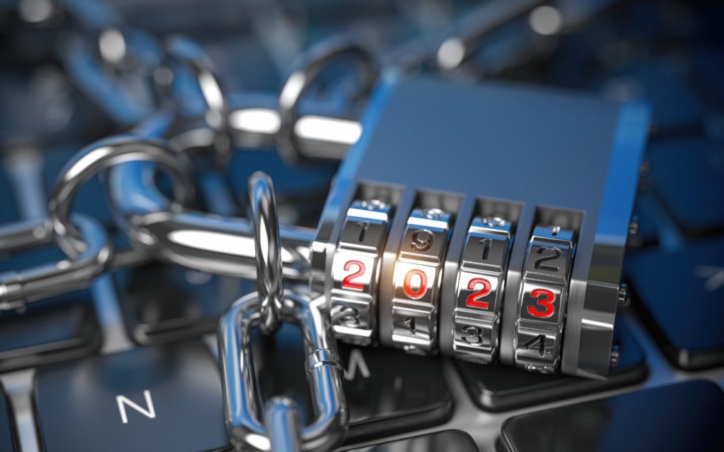 A close-up of a combination padlock displaying the numbers 2023, attached to a metal chain, resting on a black computer keyboard, symbolizing cybersecurity or data protection in 2023.