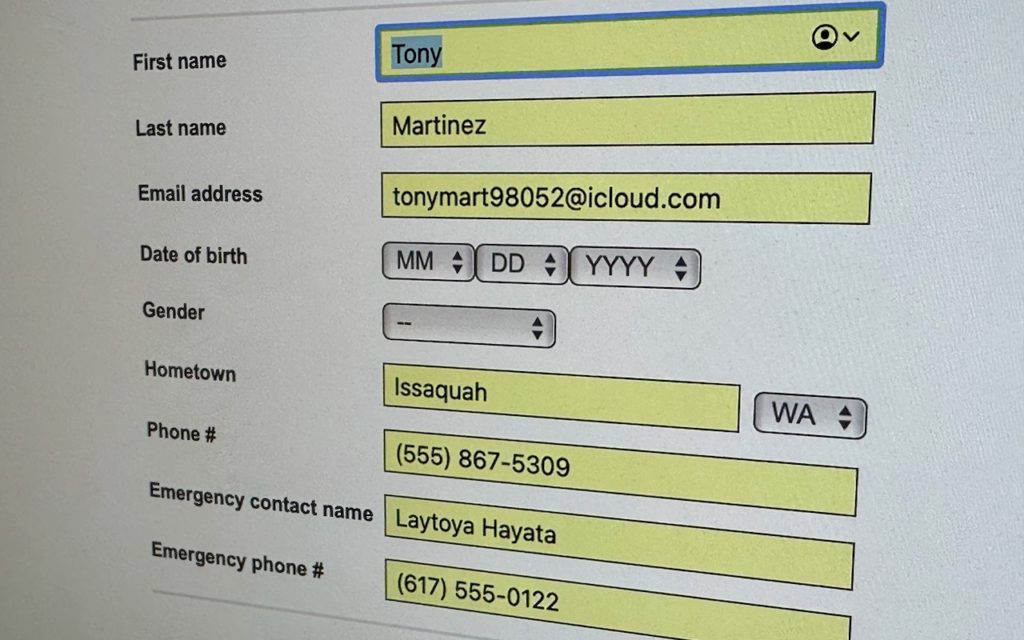 A computer screen shows a partially filled online form with fields for name, email, date of birth, gender, hometown, phone numbers, and emergency contact information highlighted in yellow.