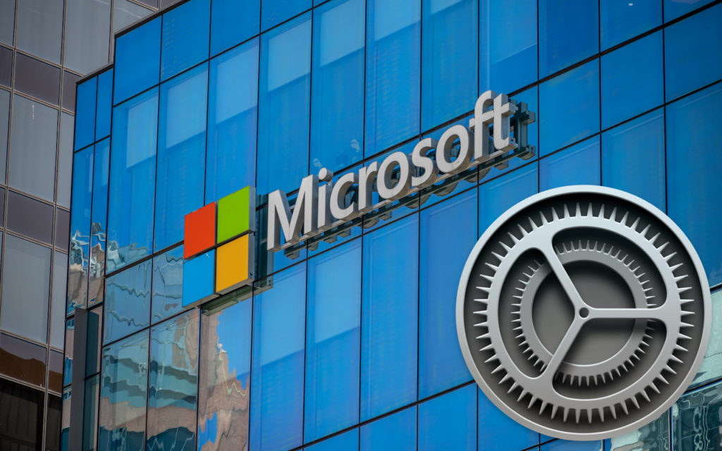 The Microsoft logo is displayed on a glass building, with a large gray settings gear icon superimposed in the foreground. The reflection of nearby structures is visible in the windows.