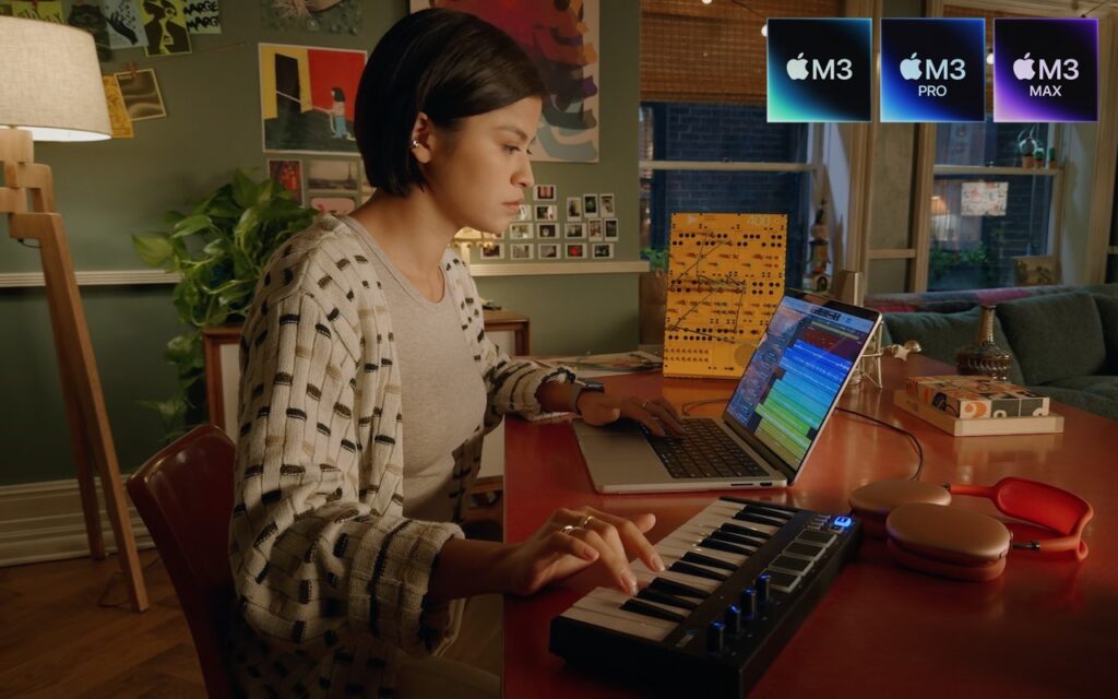 A person uses a laptop and MIDI keyboard to create music at a desk in a cozy, well-lit room. Apples M3, M3 Pro, and M3 Max chip logos appear in the top right corner.