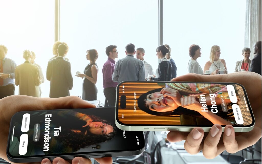 Two hands hold smartphones displaying digital profiles of “Tia Edmondson” and “Helen Chong” over a background of business professionals networking and conversing in a bright, modern office space.