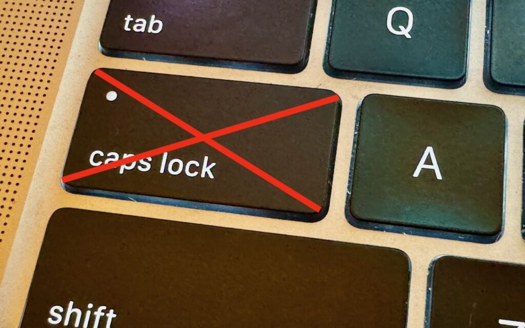A close-up of a keyboard shows the caps lock key crossed out with a large red X, indicating it should not be used. Nearby keys tab, A, and shift are also partially visible.