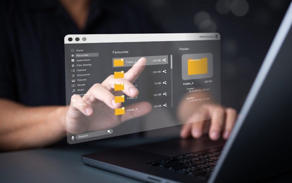 A person using a laptop interacts with a futuristic transparent screen displaying digital folders and files, illustrating advanced technology or a virtual file management system—perfect for exploring how to merge two similar folders in the Mac’s Finder.
