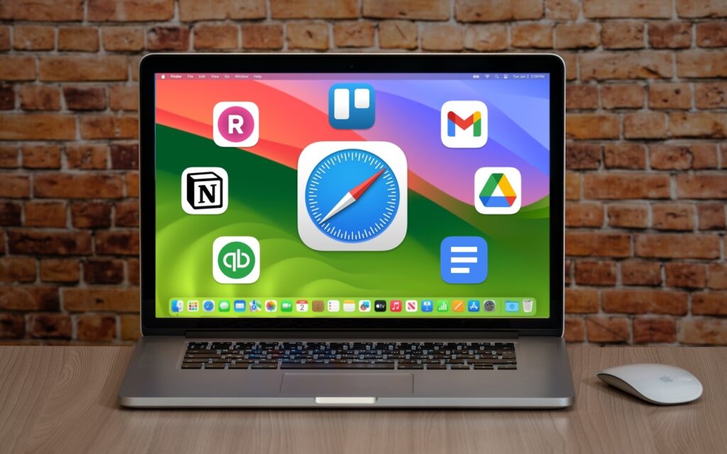 A laptop on a wooden desk displays various app icons, showing how you can Turn Your Most-Used Sites into Safari Web Apps in macOS 14 Sonoma, with apps like Gmail, Google Drive, Notion, Trello, and more against a colorful background.