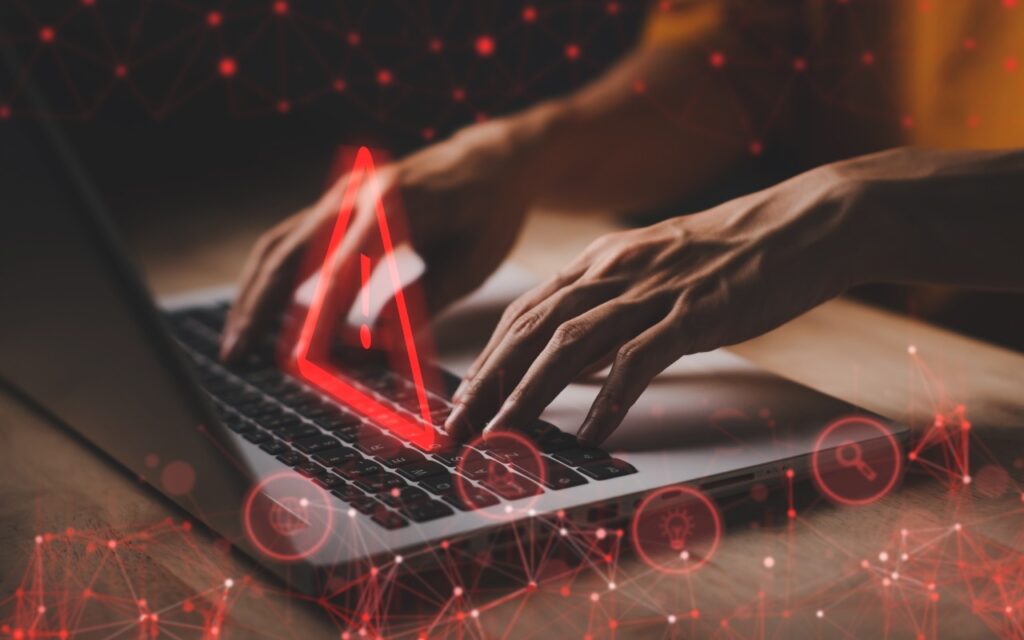Hands typing on a laptop keyboard with a glowing red warning triangle and network icons overlayed, suggesting a cybersecurity threat—perfect for illustrating the urgent question: Help! My Account Has Been Hacked—What Should I Do?.
