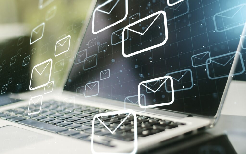 A close-up of a laptop keyboard with multiple digital envelope icons floating above the screen, symbolizing email communication and messages. The scene hints at the quest to Find Some Ham Amidst Your Email Spam. The background is softly blurred.