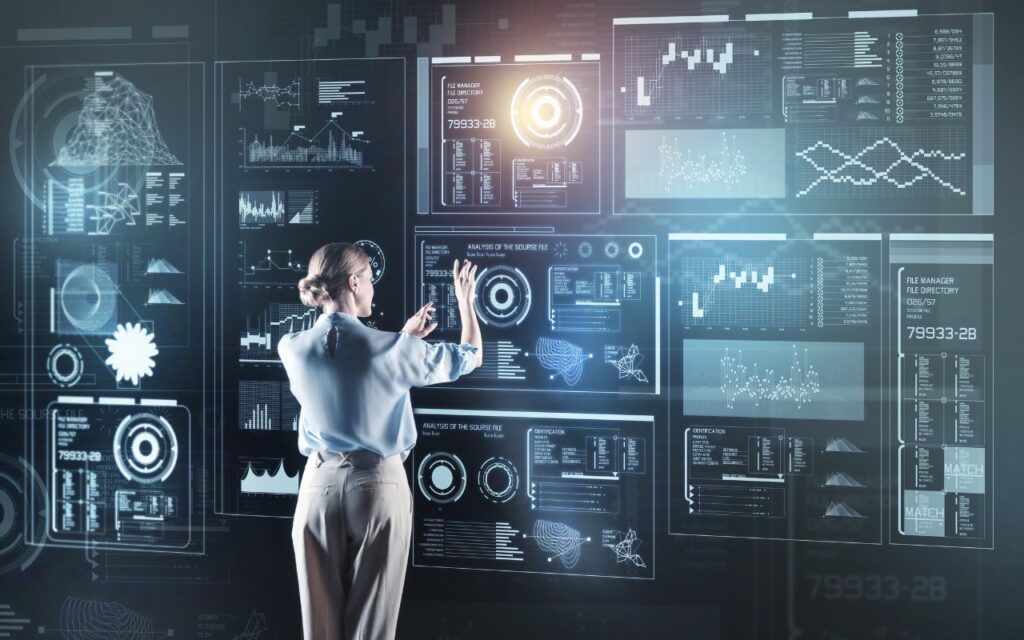 A person stands in front of a large transparent screen displaying futuristic digital data, interacting with touch gestures—much like how Control Center is now highly customizable in iOS 18 and iPadOS 18.