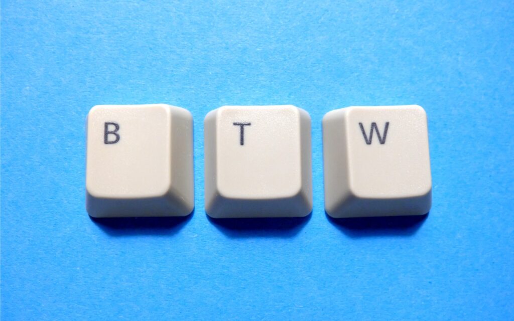 Three beige keyboard keys with the letters B, T, and W are arranged in a row on a flat, bright blue background—a perfect scene for discussing issues like "Text Replacements Not Working on the Mac? Check This Setting.