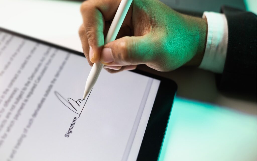 A person uses a stylus to sign an electronic document on a tablet, with the digital signature visible on the screen—showcasing how iOS 18 and iPadOS 18 offer better PDF handling in Mail.