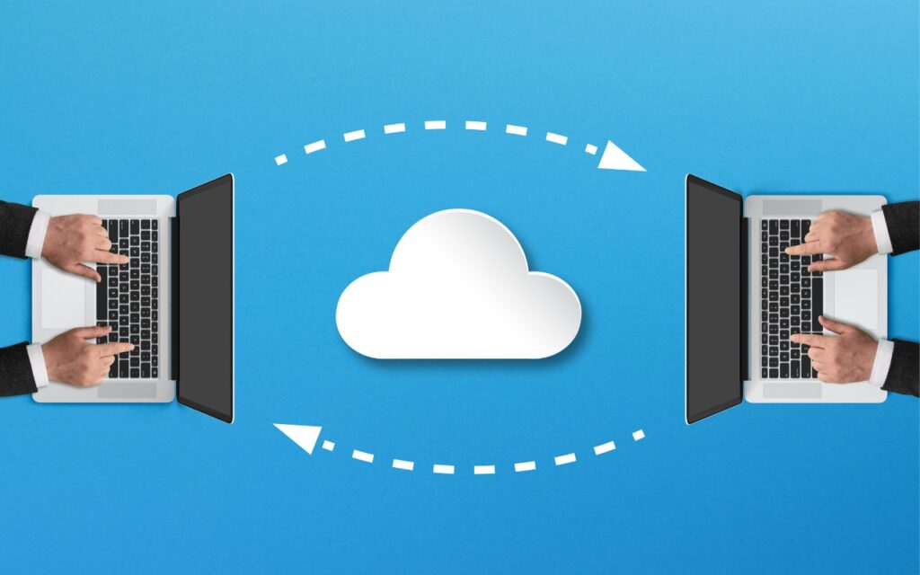 Two people typing on laptops facing each other with a cloud icon between them, connected by dotted arrows, symbolizing cloud computing or file sharing. Blue background. Try Blip for fast transfers of any size between platforms.
