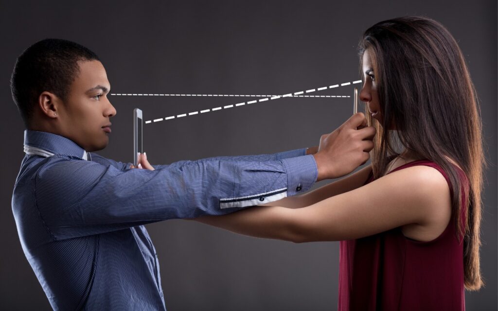 A man and woman stand facing each other, holding a phone between them at arm’s length. Dashed lines connect their eyes to the device and each other's faces, evoking both digital and personal interaction—hinting at how secondary biometrics can make Apple devices easier for family to access.
