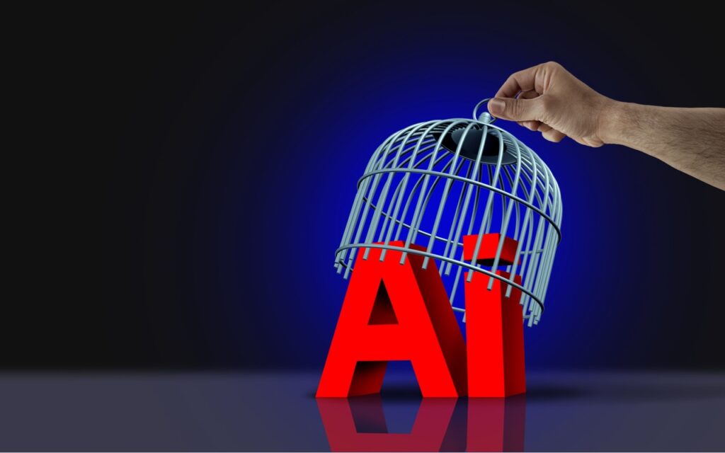 A hand lifts a birdcage off the large red letters AI against a dark background, symbolizing freeing artificial intelligence—while reminding us to Keep Sensitive Data Private by Disabling AI Training Options.