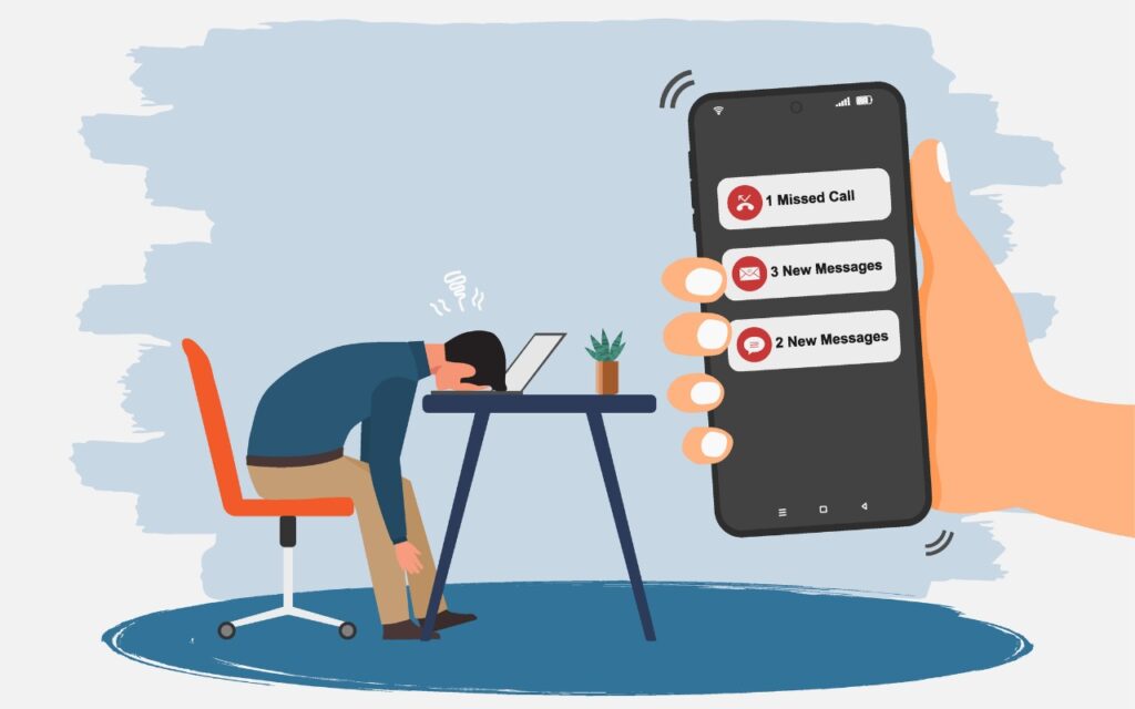 Illustration of a frustrated person with their head on a laptop at a desk, while a large hand holds a phone showing notifications—Don’t Miss Calls and Texts: How to Use New Phone and Messages Filtering.